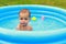 Cute shy baby boy in blue inflating pool