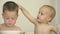 cute sibling brothers eating pasta together at table, elder boy feeding toddler