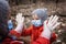 Cute sibling in red coats wearing respirator masks and medical gloves playing patty cake