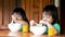 Cute sibling sisters eating boiled rice with minced pork and orange juice in the morning.