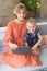 Cute siblings brother and sister sitting on sofa at home and playing on wireless tablet together