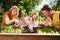 Cute siblings planting flowers with parents in garden