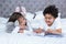 Cute siblings reading a book on the bed