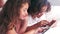 Cute siblings using tablet on their parents bed