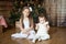 Cute sisters in front of decorated Christmas tree