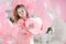 Cute six year old girl in pink dress with pink balloons in the shape of heart