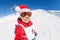 Cute skier in Santa`s hat having fun at snowy hill