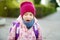 Cute sleepy little girl yawning on her way to school. Child with a backpack in a morning