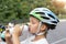 Cute small caucasian girl kid in safety sport helmet drinking fresh water from bottle after exercise bike, scooter or