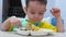 Cute small child is sitting at a table in a bib and eat his own puree, the baby eats willingly. Cute little baby eating