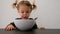 Cute small girl looking in big ceramic bowl