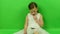 Cute small girl reads e-book on chroma key background. Little girl dressed in a romantic dress. White wedding dress