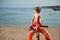 Cute small kid in sunglasses sitting on beach with lifebuoy outdoor summer