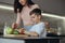 Cute small teen boy helping mother to cook and prepare food in kitchen. Vegetables.