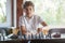 Cute, smart, 11 years old boy in white shirt sits in the classroom and plays chess on the chessboard. Training, lesson, hobby