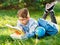 Cute, smart, young boy in blue shirt sits on the grass next to his school backpack, globe, chalkboard, workbooks. Education