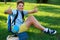 Cute, smart, young boy in blue shirt sits on the grass next to his school backpack, globe, chalkboard, workbooks. Education