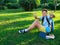 Cute, smart, young boy in blue shirt sits on the grass next to his school backpack, globe, chalkboard, workbooks. Education