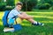 Cute, smart, young boy in blue shirt sits on the grass next to his school backpack, globe, chalkboard, workbooks. Education