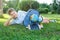 Cute, smart, young boy in blue shirt sits on the grass next to his school backpack, globe, chalkboard, workbooks. Education