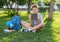 Cute, smart, young boy in blue shirt sits on the grass next to his school backpack, globe, chalkboard, workbooks. Education