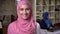 Cute smile of muslim female in pink hijab standing, office working mood, brick studio indoor, middle east vibes