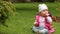 Cute smiling baby-girl crawling on a green grass in the city park.