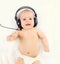 Cute smiling baby listens to music in headphones lying on bed