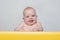 Cute smiling baby looking at the camera. Toddler sits at the table