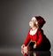 Cute smiling barefooted child boy toddler is sitting in santa claus costume on ice looking up in corner at copy space