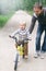 Cute smiling blond boy learning to ride bicycle. Father teaching his little child to ride bike in spring summer park. Happy family