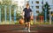 Cute smiling boy in blue t shirt plays basketball on city playground. Active teen enjoying outdoor game with orange ball.