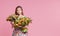 Cute smiling child girl holding bouquet of spring flowers tulips isolated on pink background. Little toddler girl gives a bouquet