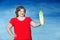 Cute smiling chubby red-haired woman holds out celery against a blue background