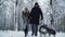 Cute smiling couple walking together with two beautiful siberian fluffy huskies in the winter snowy forest