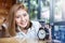 Cute smiling girl with alarm clock on wooden table