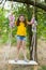 Cute smiling girl having fun on a swing in tree forest