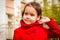 Cute smiling girl in a red coat and tucks her hair