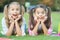 Cute smiling kids sisters relax green grass, real surprise concept