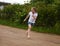 A cute smiling little girl running barefoot in a countryside landscape along a country path