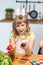 Cute smiling little girl show painted Easter eggs at her hands at kitchen