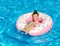 Cute smiling little girl in swimming pool with rubber ring. Child having fun on vacation