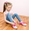 Cute smiling little girl tying her shoes