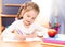 Cute smiling little girl is writing at the desk