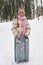 Cute smiling pre-teen girl in winterwear holding toboggan sledge