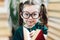 Cute smiling preschool age girl with dimples in round big glasses with red book in her hands looking at a camera