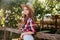 Cute smiling redhead cowgirl in hat leaning on ranch fence