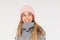 Cute smiling teenage girl in pink knitted hat and cozy gray poncho isolated on the white background