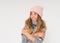 Cute smiling teenage girl in pink knitted hat and cozy gray poncho isolated on the white background