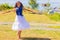 A cute smiling teenage girl is whirling in a meadow in a light dress with bare feet.